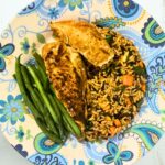 Pan seared chicken breasts with vegetable wild rice and haricot verts served on a white plate with blue filigree
