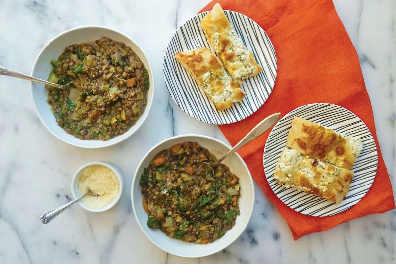 bowl of lentil stew with focaccia bread on the side