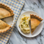 savory pie on a white plate with checkered blue and white napkin underneath