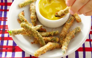Crispy breaded green bean fries being dipped in sauce