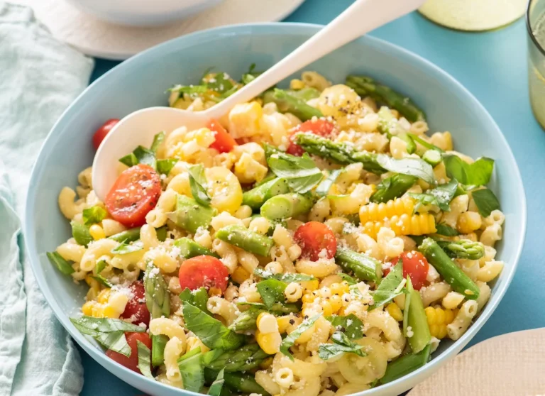Summer pasta salad with corn, asparagus and tomatoes in a blue bowl