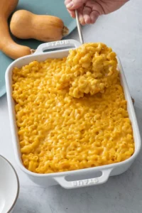 Butternut squash mac and cheese being scooped from a baking dish