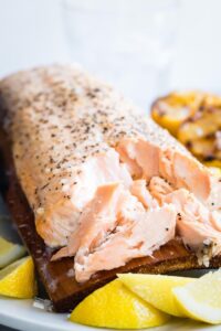 Cedar plank salmon flaked open with lemon wedges