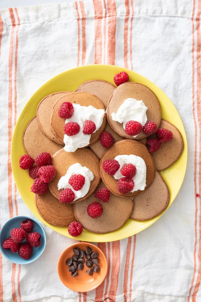 Chocolate pancakes topped with yogurt and raspberries