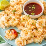 Coconut baked shrimp on a plate with a bowl of dipping sauce