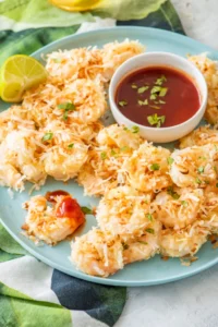 Coconut baked shrimp on a plate with a bowl of dipping sauce