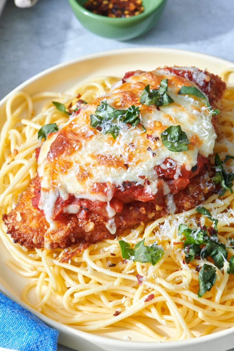 Crispy chicken parmesan with melted cheese and basil over spaghetti