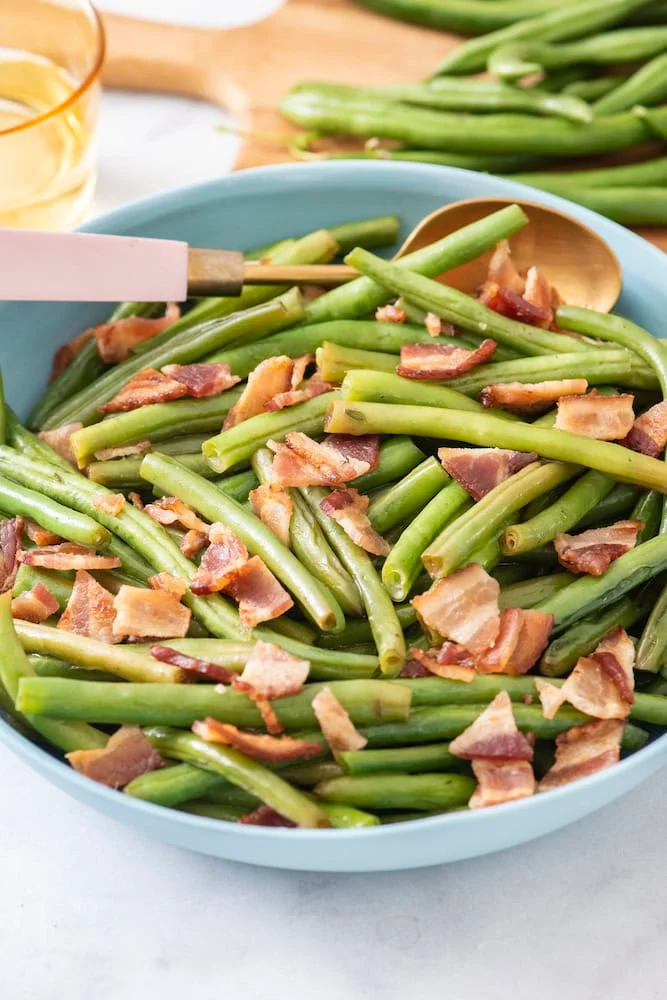 Sautéed green beans with bacon in a blue bowl