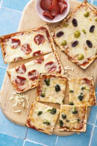 Matzah pizzas topped with mozzarella, pepperoni and olives