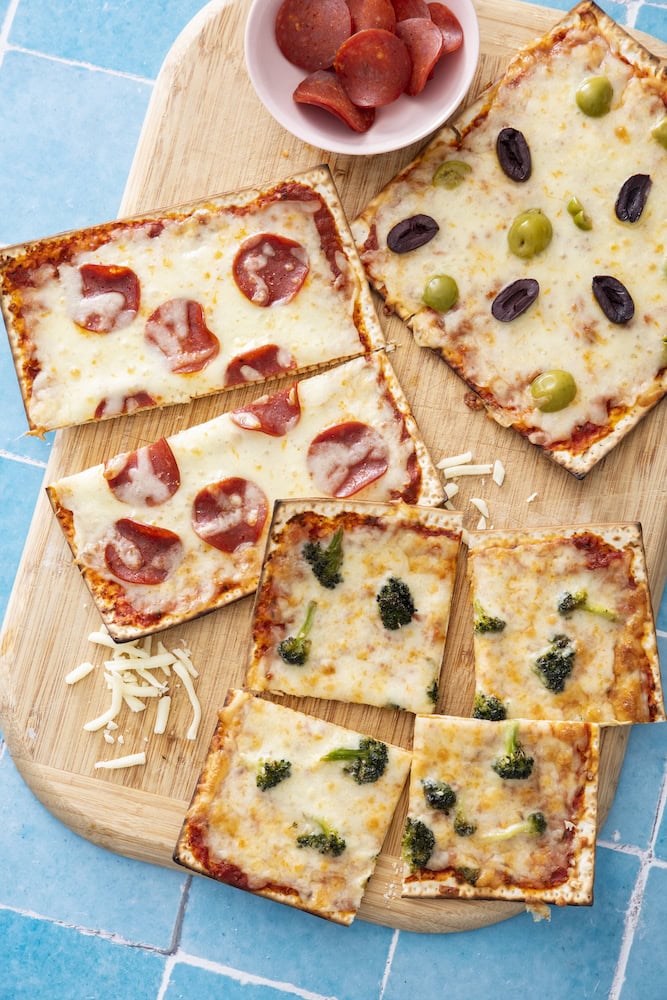 Matzah pizzas topped with mozzarella, pepperoni and olives