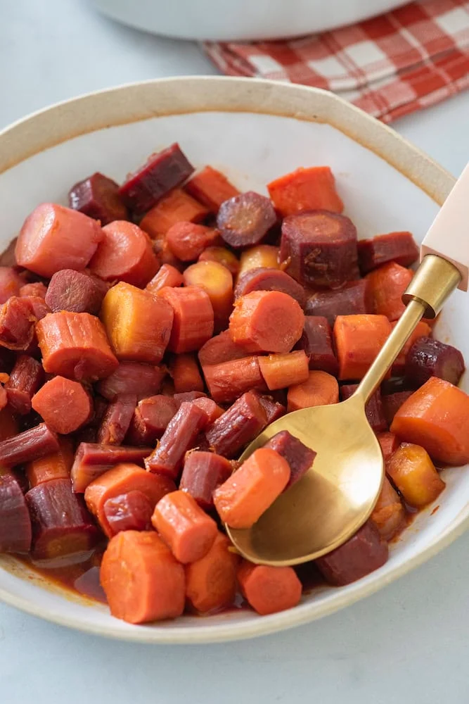 Orange-glazed rainbow carrots in a white bowl
