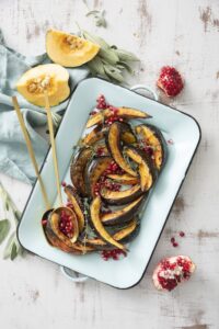 Roasted acorn squash slices with pomegranate seeds on a platter