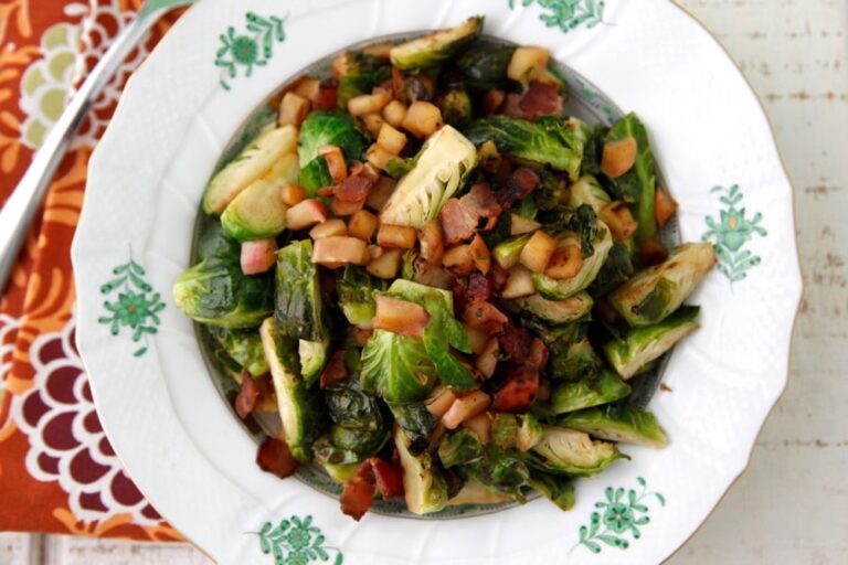 Sautéed Brussels sprouts with bacon and apple on a white plate