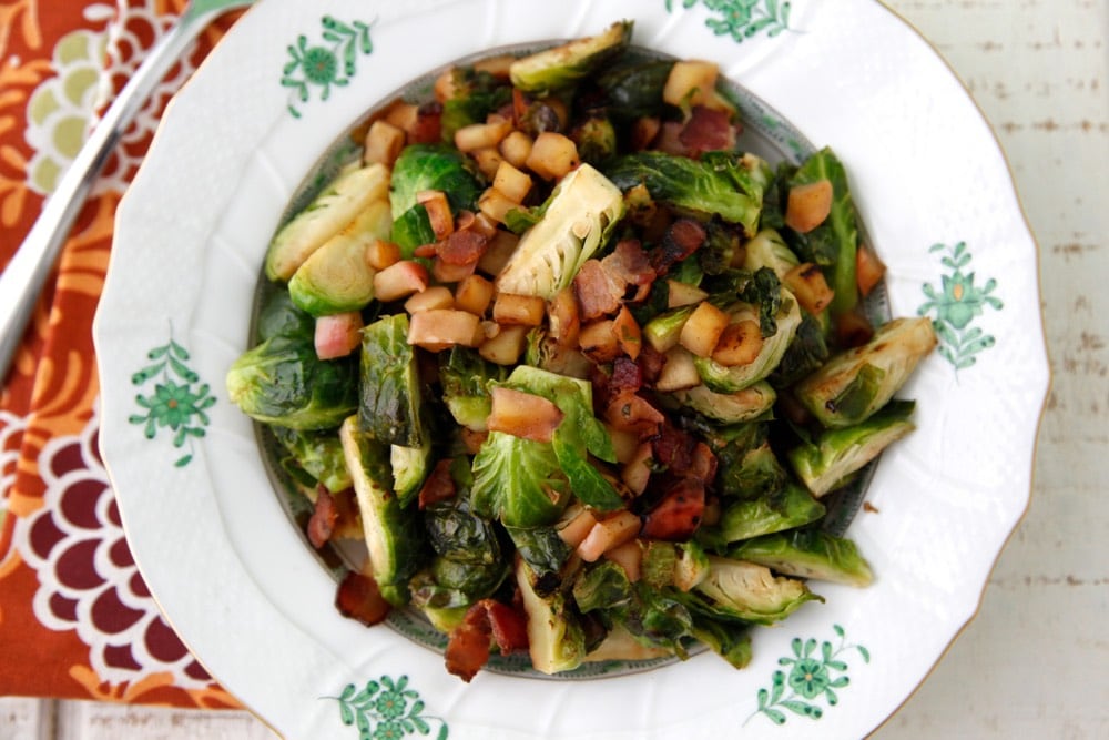 Sautéed Brussels sprouts with bacon and apple on a white plate