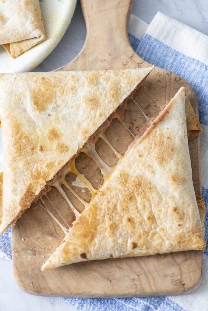 Crispy folded bean and cheese tortilla pillows cut in half