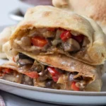 Vegetarian calzone cut open to show peppers and mushrooms