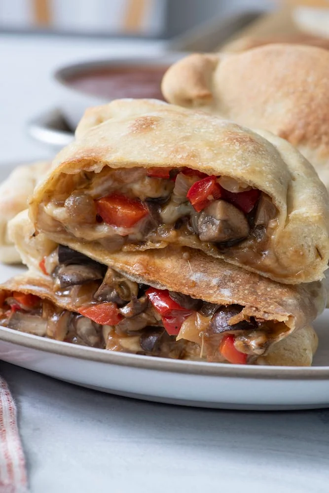 Vegetarian calzone cut open to show peppers and mushrooms