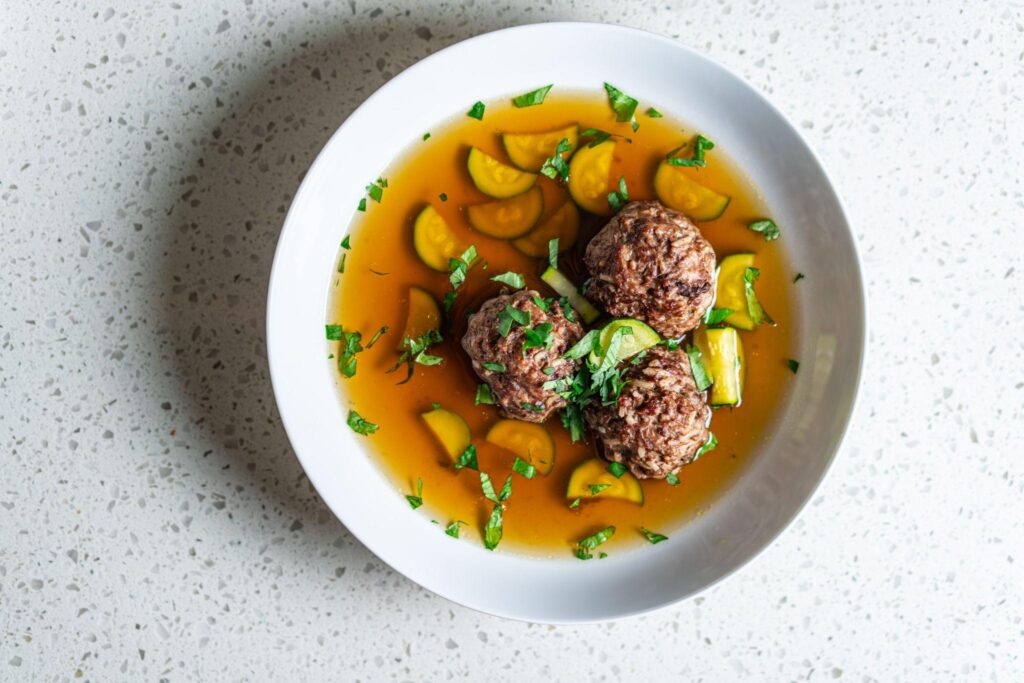 A bowl of albóndigas, Mexican meatball soup with zucchini in broth