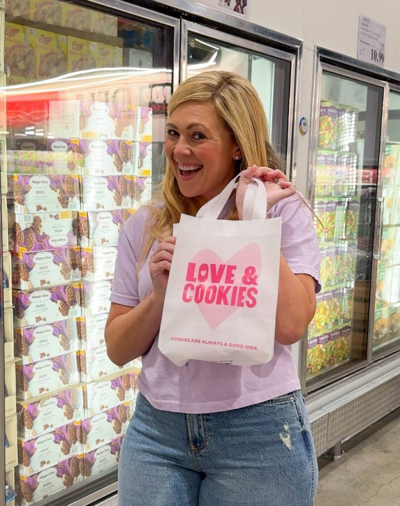 Ashley holding a Love & Cookies bag in the freezer isle of a grocery store