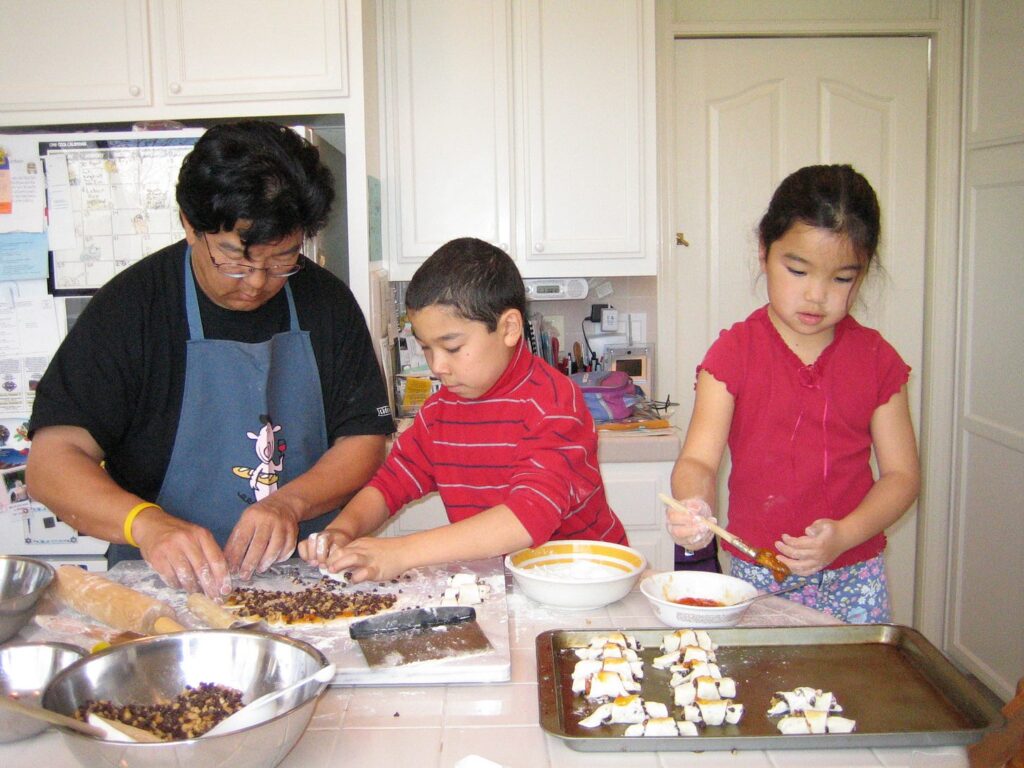 Korean-American dad standing at a kitchen counter making rugelach with his son and daughter