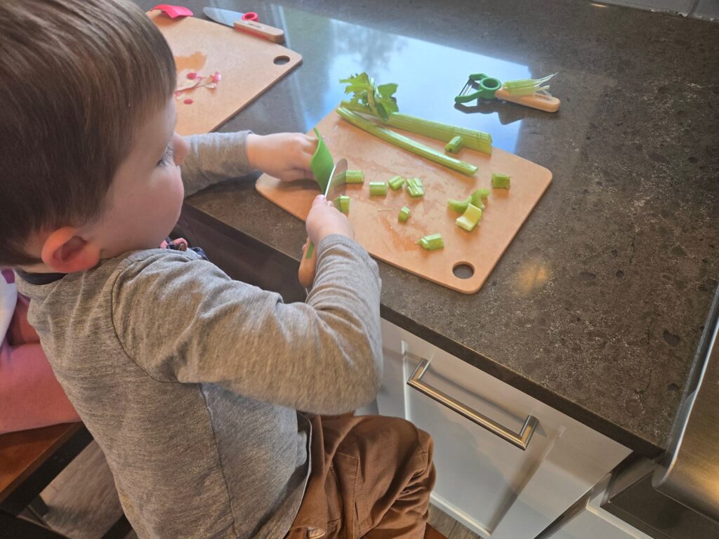 A young boy chopping celery on a cutting board