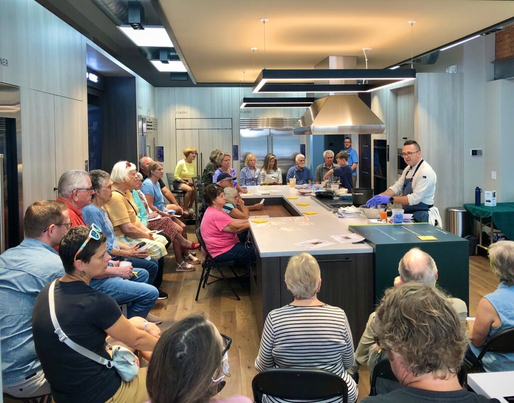 Chef Bob Bennett and his son Lucas giving a cooking demo to a full room