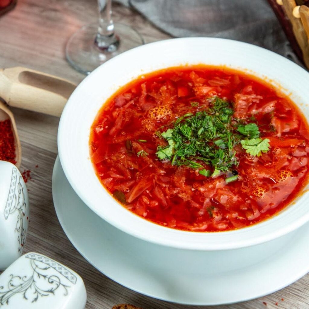 Large white bowl full of borscht with shredded fresh parsley garnish