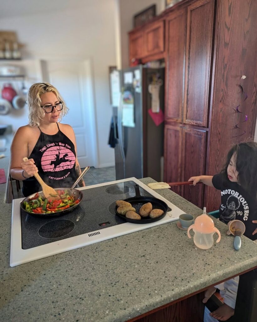 A latina woman stands at the kitchen counter with a young girl, approximately 3 years of age.