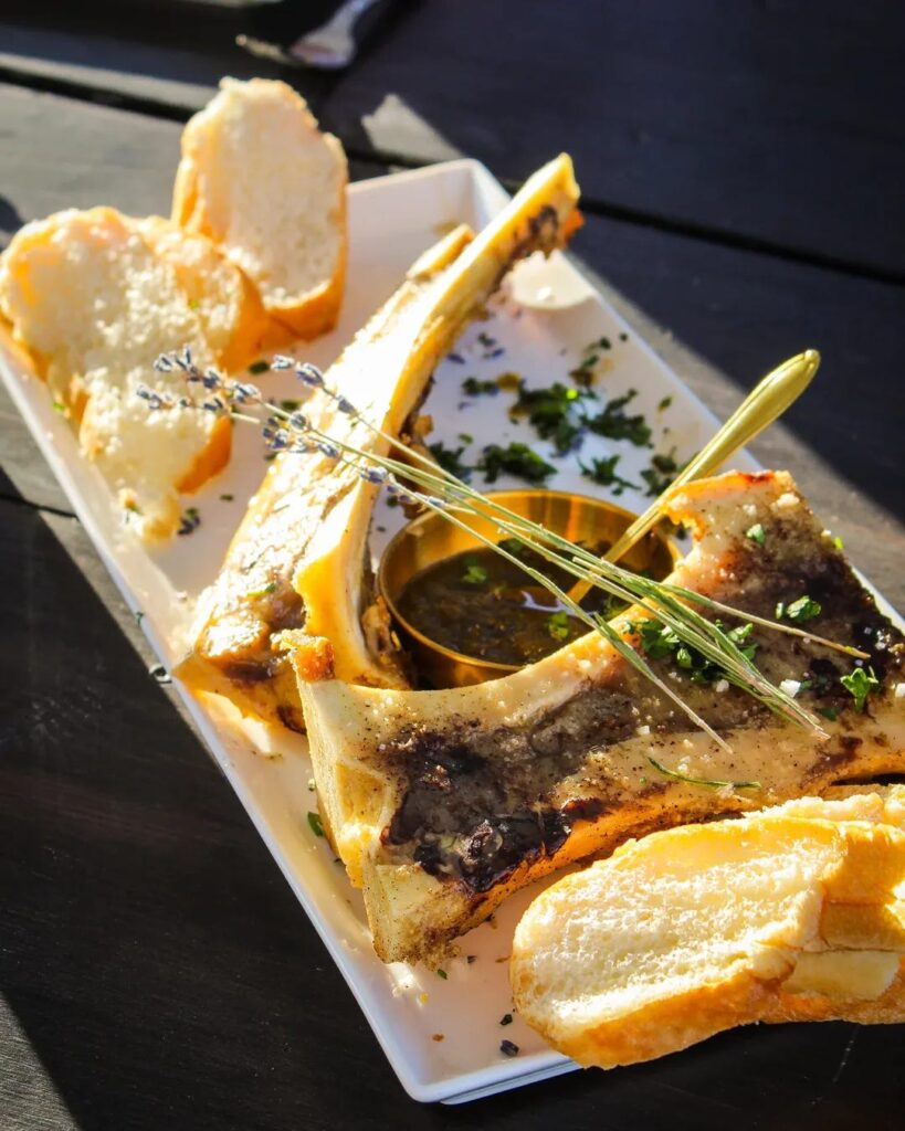 elegant white dinner plate filled with local roasted bone marrow with grilled bread, citrus Mexican sea salt , toreado inspired jalapeño-lavender jam