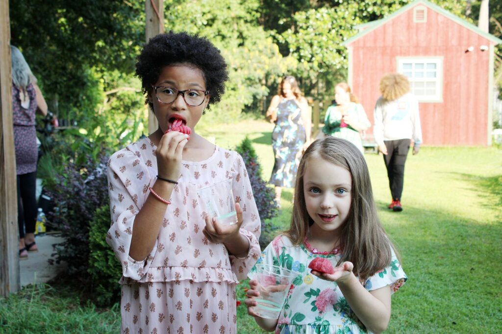 Young African American Girl and her caucasian friend eating a red fruit