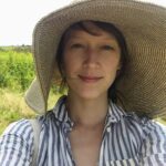 Cathy Erway outdoors in a wide straw sun hat and striped shirt