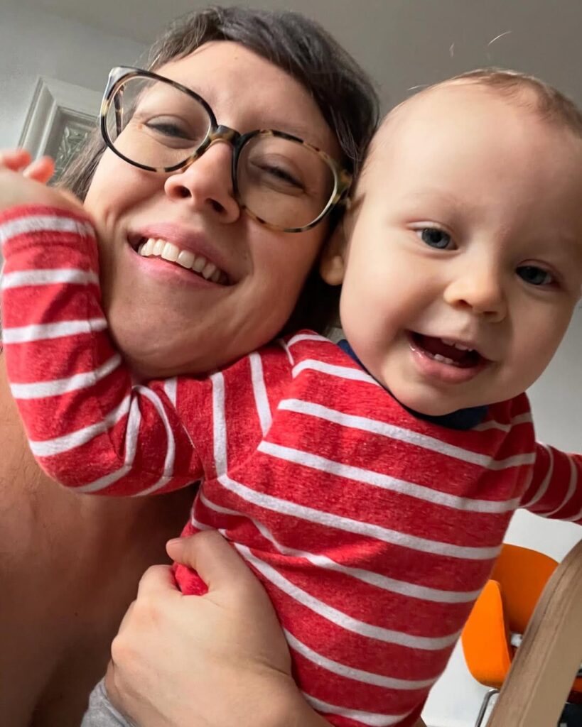Cathy Erway smiling with her baby son in a red striped shirt
