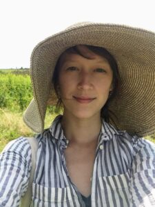 Cathy Erway outdoors in a wide straw sun hat and striped shirt