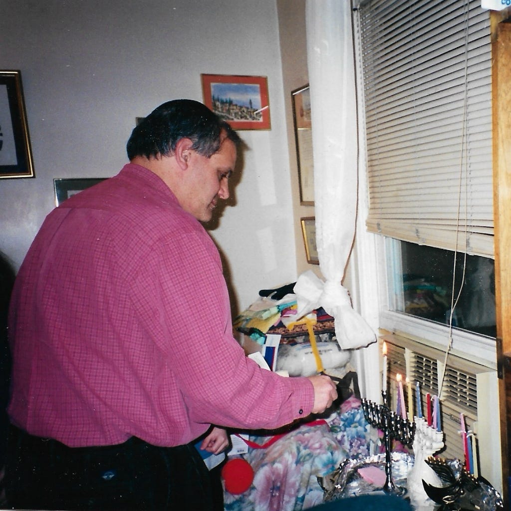 Ellen’s husband lighting the Chanukah candles by a window