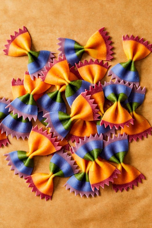 rainbow colored bow tie pasta on a sand colored background