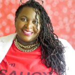 Demetra Overton looking at camera smiling in red shirt and white blazer