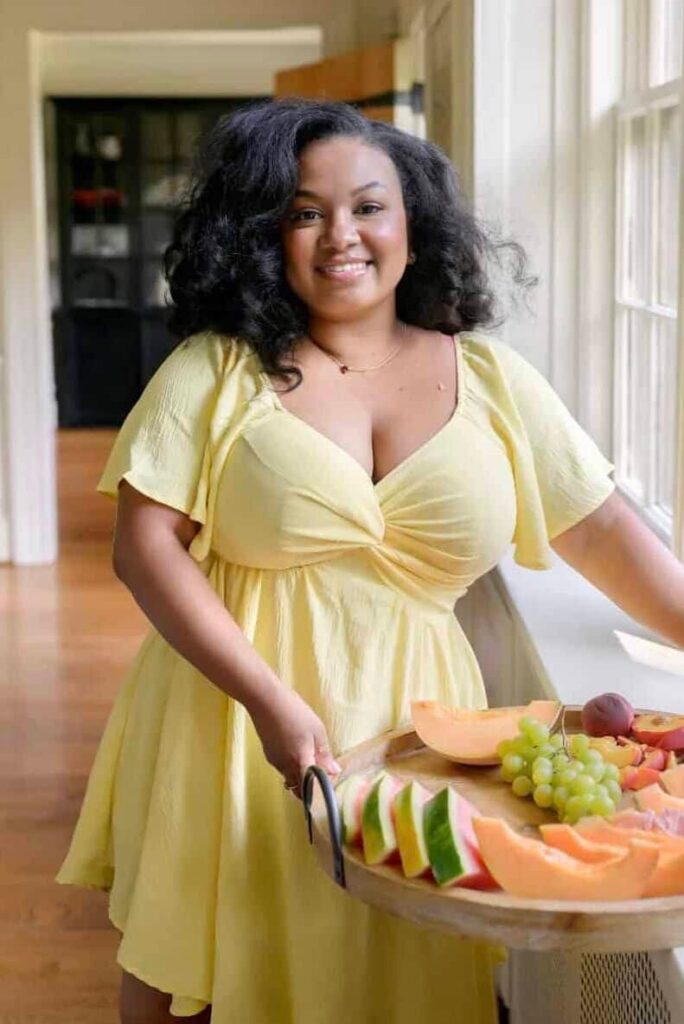 Eden Westbrook in a yellow dress with a try of fruit