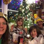 Emily and her family in paper crowns at their Christmas dinner table, in front of the tree