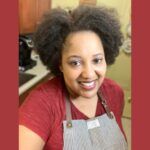 Chef Cassandra Loftlin smiling in her kitchen in a striped apron