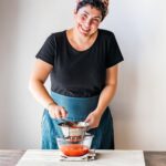 Giulia Scarpaleggia wearing a black t shirt and prepping food in the kitchen