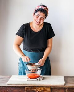 Giulia Scarpaleggia wearing a black t shirt and prepping food in the kitchen