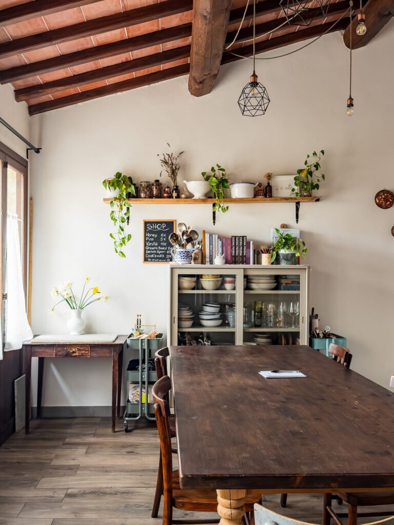 Giulia Scarpaleggia's home kitchen in Tuscany, with a long wooden table, open shelves and a beamed ceiling