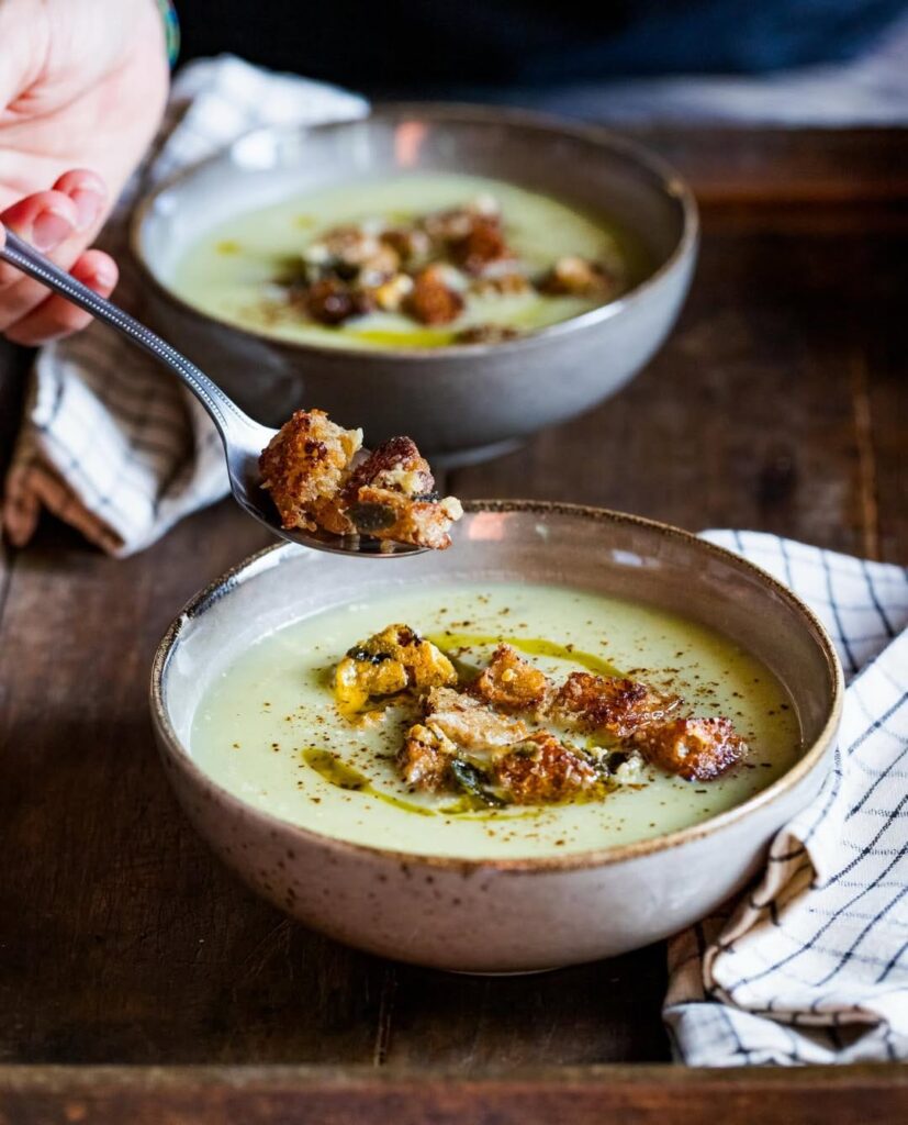 two grey bowls filled with soup and topped with crutons