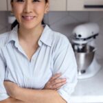 Jane Nicholson standing in her kitchen in a polo shirt and yellow headband