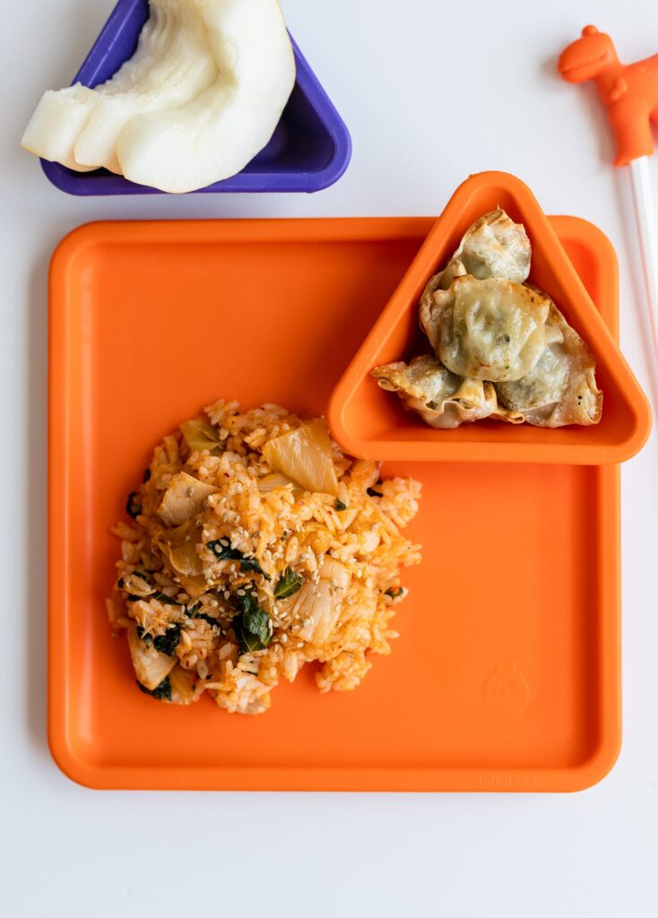Kimchi kale fried rice and dumplings on orange square plate