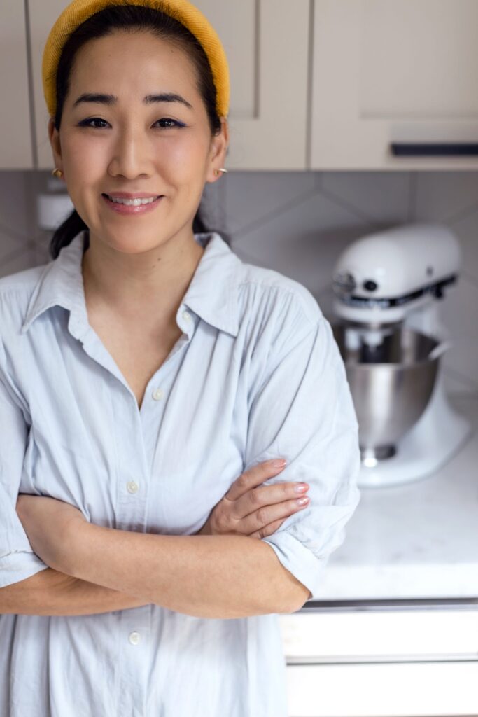 Jane Nicholson standing in her kitchen in a polo shirt and yellow headband