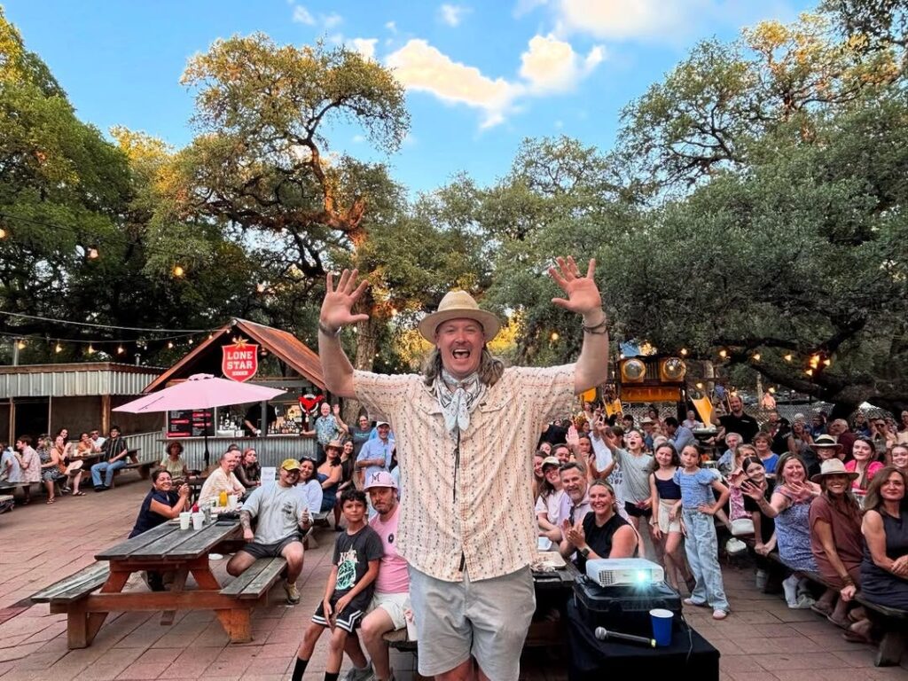 Chef Jason outside at his restaurant, Two Bros BBQ Market with customers sitting at picnic tables