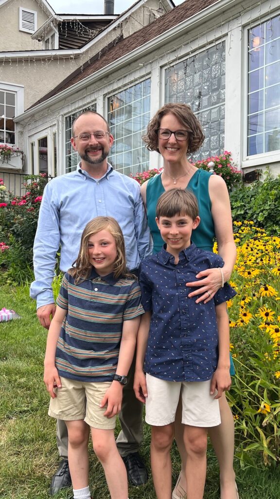 Jennifer Anderson, her husband, and two kids outside surrounded by wild flowers