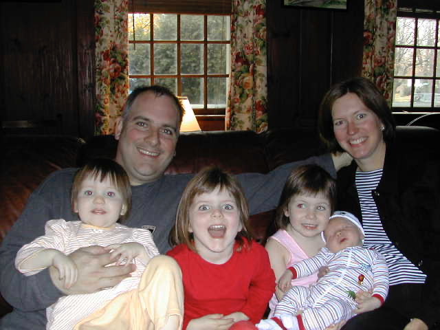 Jill and her husband sitting on the couch with her four children