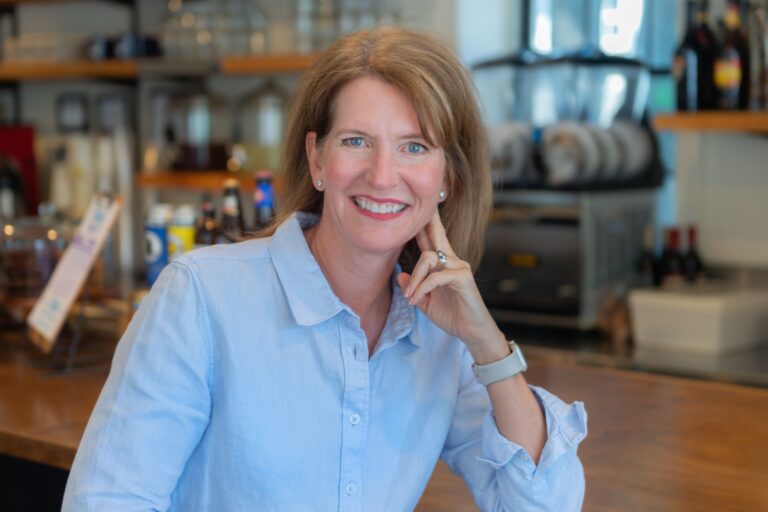 Jill Castle sitting in her kitchen wearing a light blue shirt